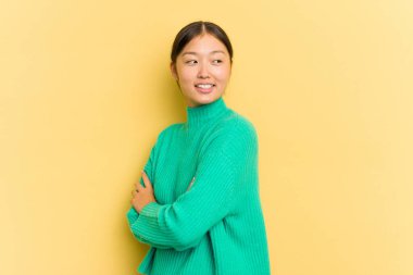 Sarı arka planda yalnız yaşayan genç Asyalı kadın gülüyor ve eğleniyor..