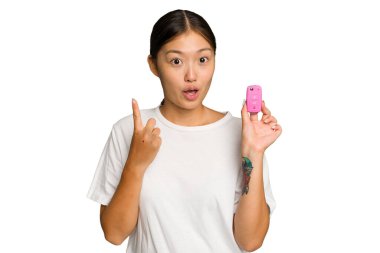 Asyalı genç bir kadının elinde yeşil renkli arka planda izole edilmiş araba anahtarları var. Harika bir fikri var, yaratıcılık kavramı..