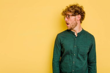 Sarı arka planda izole edilmiş genç beyaz adam gördüğü bir şey yüzünden şoka uğruyor..