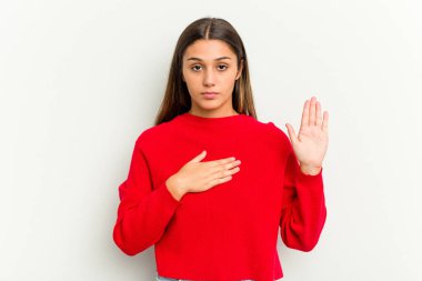 Genç Hintli kadın beyaz arka planda izole edilmiş yemin ediyor, elini göğsüne koyuyor..