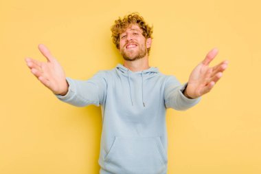 Sarı arka planda izole edilmiş genç beyaz adam kameraya sarıldığı için kendinden emin hissediyor..