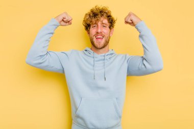 Sarı arka planda izole edilmiş genç beyaz adam güçlü bir hareket sergiliyor, kadınsı gücün sembolü.