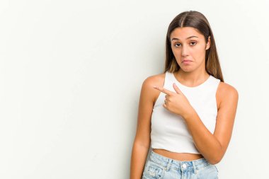 Beyaz arka planda izole edilmiş genç bir Hintli kadın gülümsüyor ve boş alanda bir şeyler gösteriyor..