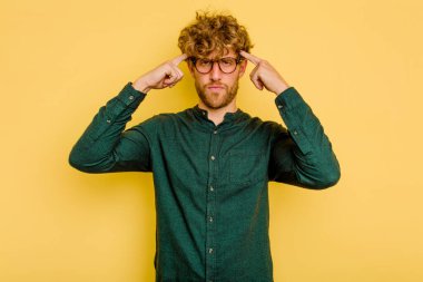 Sarı arka planda izole edilmiş genç beyaz adam bir göreve odaklanmış, işaret parmaklarını işaret ediyor..