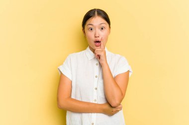 Asyalı genç bir kadın sarı arka planda izole edilmiş. Yaratıcılık kavramı hakkında harika bir fikri var..