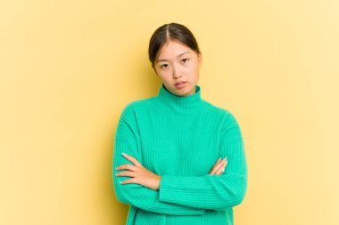 Sarı arka planda izole edilmiş genç Asyalı kadın sıkılmış, yorgun ve dinlenmeye ihtiyacı var..