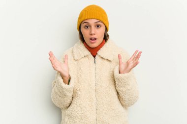 Kışlık ceket giyen genç Hintli kadın beyaz arka planda izole edilmiş şaşırmış ve şok olmuş..