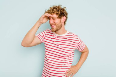 Kafkasyalı genç adam mavi arka planda izole edilmiş neşeli bir şekilde gülüyor. Mutluluk kavramı.