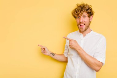 Sarı arka planda izole edilmiş genç beyaz adam işaret fişekleriyle işaret ederek heyecanlanıyor..