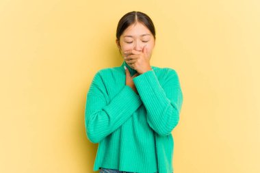 Sarı arka planda izole edilmiş genç Asyalı kadın virüs ya da enfeksiyon yüzünden boğaz ağrısı çekiyor..