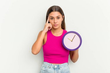 Elinde beyaz arka planda izole edilmiş bir saat tutan genç Hintli kadın parmağıyla tapınağı işaret ediyor, düşünüyor ve bir göreve odaklanıyor..