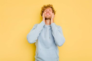 Kafkasyalı genç adam sarı arka planda izole edilmiş sızlanıyor ve ağlıyordu..