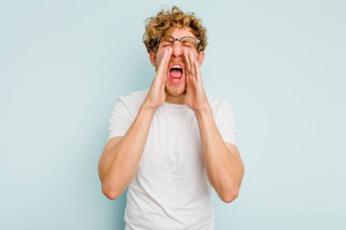 Mavi arka planda izole edilmiş beyaz bir adam heyecanlı bir şekilde bağırıyor..