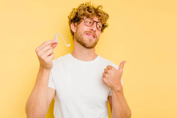 Jonge Blanke Man Met Gehoorapparaat Geïsoleerd Gele Achtergrond Met Duimvinger — Stockfoto
