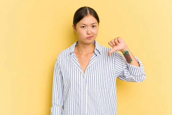 親指を示す黄色の背景に隔離された若いアジアの女性 失望の概念 — ストック写真
