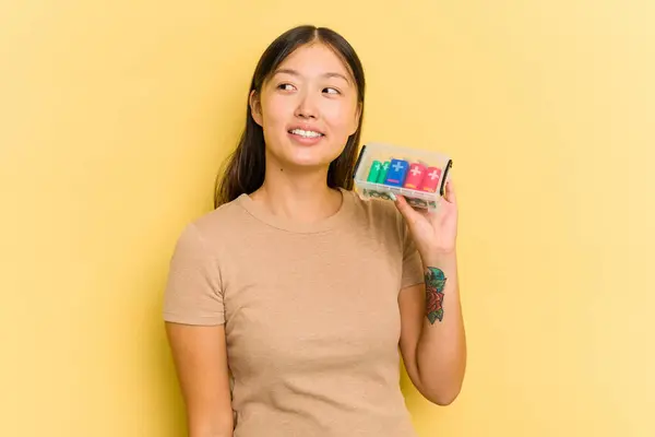 黄色の背景に隔離された電池を持っている若いアジアの女性は笑顔 陽気で楽しい脇に見えます — ストック写真
