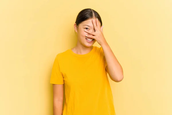 Jovem Ásia Mulher Isolado Amarelo Fundo Piscar Câmera Através Dedos — Fotografia de Stock
