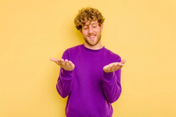 Jovem Caucasiano Isolado Fundo Amarelo Segurando Algo Com Palmas Das — Fotografia de Stock