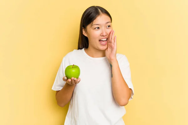 Giovane Donna Asiatica Mangiare Una Mela Isolata Sfondo Giallo Gridando — Foto Stock