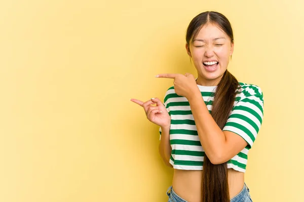 被黄色背景隔离的年轻亚洲女人兴奋地伸出食指 — 图库照片