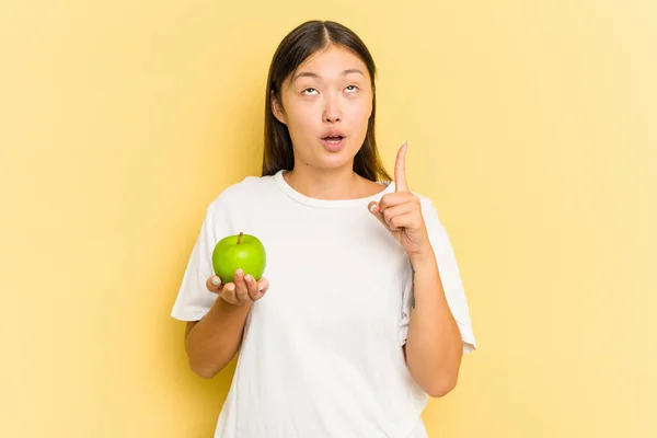 Joven Asiática Comiendo Una Manzana Aislada Sobre Fondo Amarillo Apuntando —  Fotos de Stock