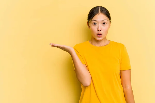 Young Asian Woman Isolated Yellow Background Impressed Holding Copy Space — Stock Photo, Image