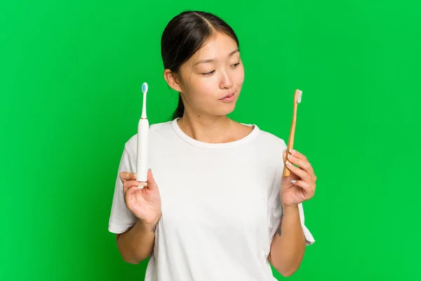 Junge Asiatin Mit Elektrischer Zahnbürste Auf Grünem Hintergrund — Stockfoto