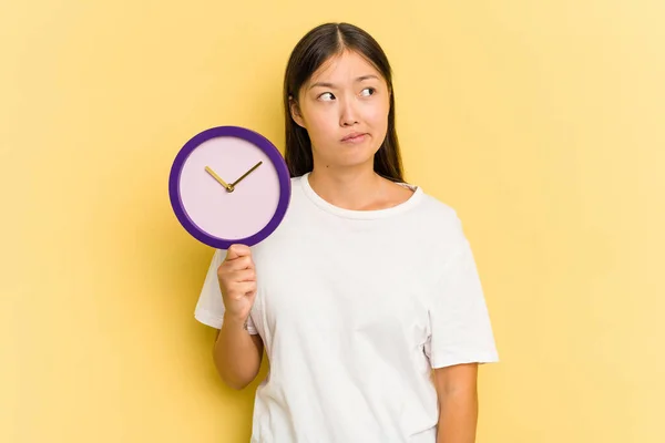 Junge Asiatische Frau Hält Eine Uhr Isoliert Auf Gelbem Hintergrund — Stockfoto