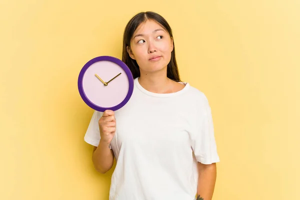 Junge Asiatische Frau Hält Eine Uhr Auf Gelbem Hintergrund Und — Stockfoto