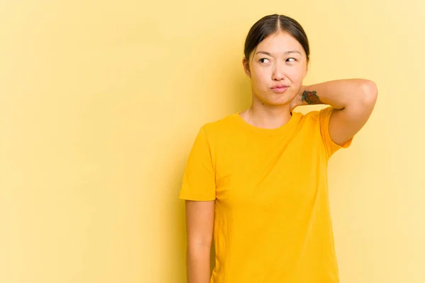 Young Asian Woman Isolated Yellow Background Touching Back Head Thinking — Stock Photo, Image