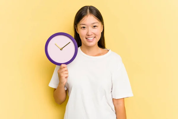 Jonge Aziatische Vrouw Met Een Klok Geïsoleerd Gele Achtergrond Gelukkig — Stockfoto