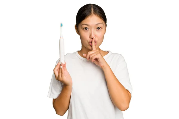 年轻的亚洲女人拿着用绿色底色隔开的电动牙刷保守秘密或要求安静 — 图库照片