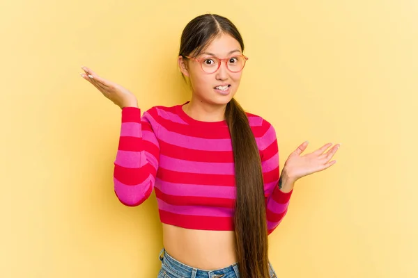 Junge Asiatin Isoliert Auf Gelbem Hintergrund Verwirrt Und Zweifelhaft Achselzuckend — Stockfoto