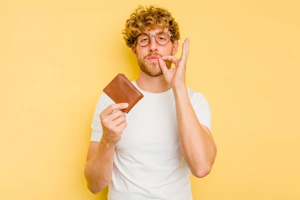 Young Caucasian Man Holding Wallet Isolated Yellow Background Fingers Lips — Stock Photo, Image