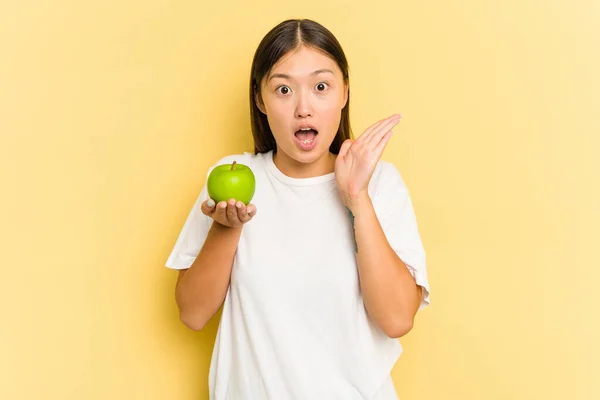Junge Asiatin Isst Einen Apfel Isoliert Auf Gelbem Hintergrund Überrascht — Stockfoto