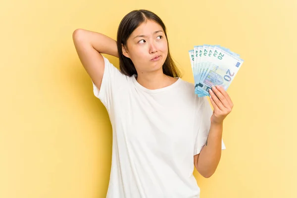 Young Asian Woman Holding Banknotes Isolated Yellow Background Touching Back — Stock Photo, Image