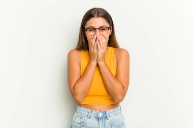 Beyaz arka planda izole edilmiş genç bir Hintli kadın bir şeye gülüyor, elleriyle ağzını kapatıyor..