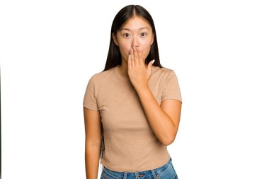 Genç Asyalı kadın yeşil renkli arka planda izole edilmiş şok geçirmiş, ağzı ellerle kaplanmış, yeni bir şey keşfetmeye hevesli..