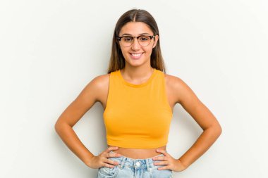 Genç Hintli bir kadın beyaz arka planda izole edilmiş, kendine güvenen ellerini kalçasında tutan..