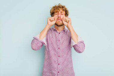 Kafkasyalı genç adam mavi arka planda izole edilmiş sızlanıyor ve ağlıyordu..