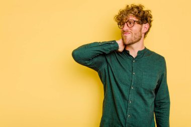 Kafkasyalı genç adam sarı arka planda izole edilmiş kafasının arkasına dokunuyor, düşünüyor ve bir seçim yapıyor..