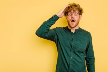 Sarı arka planda izole edilmiş genç beyaz adam yüksek sesle bağırıyor, gözleri açık ve elleri gergin tutuyor..