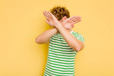 Sarı arka planda izole genç beyaz adam iki kolu çapraz tutuyor, inkar kavramı.