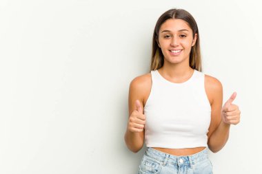 Genç Hintli kadın beyaz arka planda izole edilmiş gülümsüyor ve başparmağını kaldırıyor.