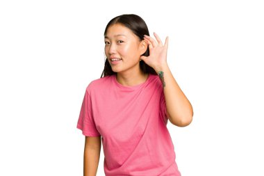 Genç Asyalı kadın yeşil renkli arka planda izole edilmiş bir şekilde bir dedikoduyu dinlemeye çalışıyor..