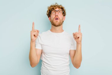 Mavi arka planda izole edilmiş beyaz bir adam ağzı açık bir şekilde üst tarafı işaret ediyor..