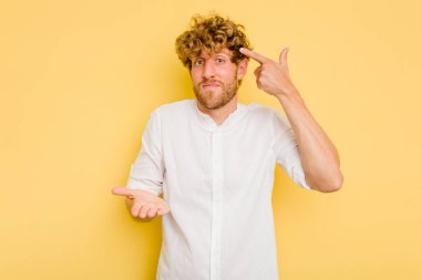 Genç beyaz adam sarı arka planda izole edilmiş ve elinde bir ürün var..