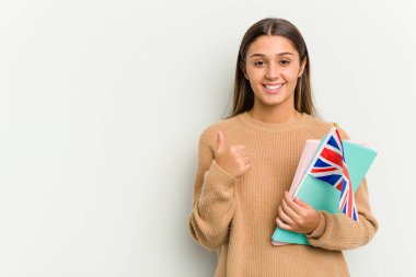 Beyaz arka planda izole edilmiş bir Birleşik Krallık bayrağı tutan genç Hintli kadın gülümsüyor ve başparmağını kaldırıyor.
