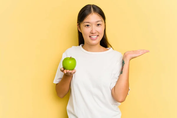 Giovane Donna Asiatica Mangiare Una Mela Isolata Sfondo Giallo Mostrando — Foto Stock