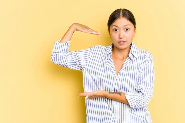 Mujer Asiática Joven Aislada Sobre Fondo Amarillo Sorprendida Sorprendida Sosteniendo — Foto de Stock